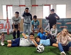 Kinder posieren mit Fußball vor dem Fußballtor