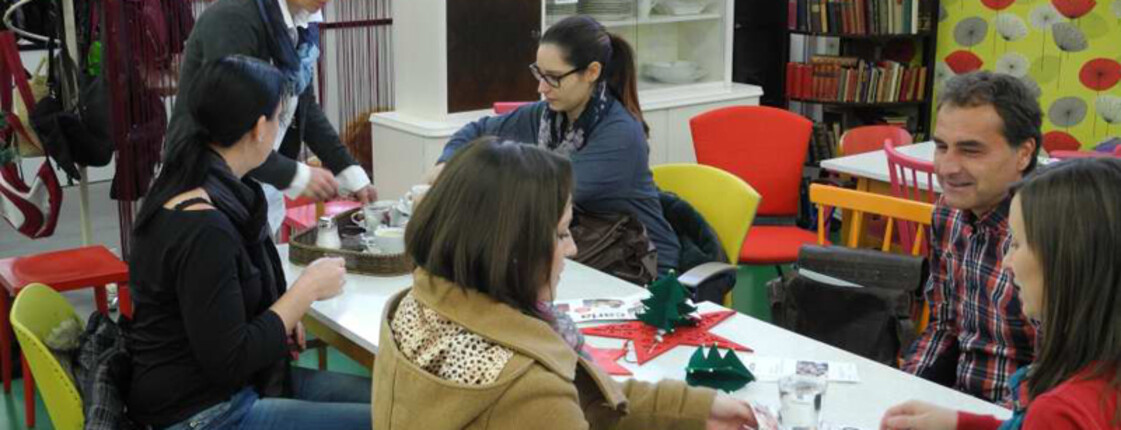 Viele Frauen versammeln sich an einem langen Tisch und basteln. Sie befinden sich im Carla Haus.