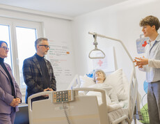 Ein Schüler und zwei Erwachsene vor einer Pflegepuppe