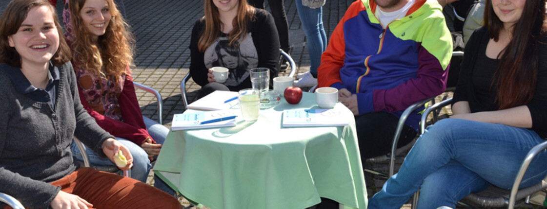 Junge Erwachsene sitzen an einem kleinen runden Tisch beim Generationen Talk. 
