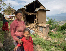 Eine Frau steht mit ihrer Tochter vor den Trümmern ihres Hauses