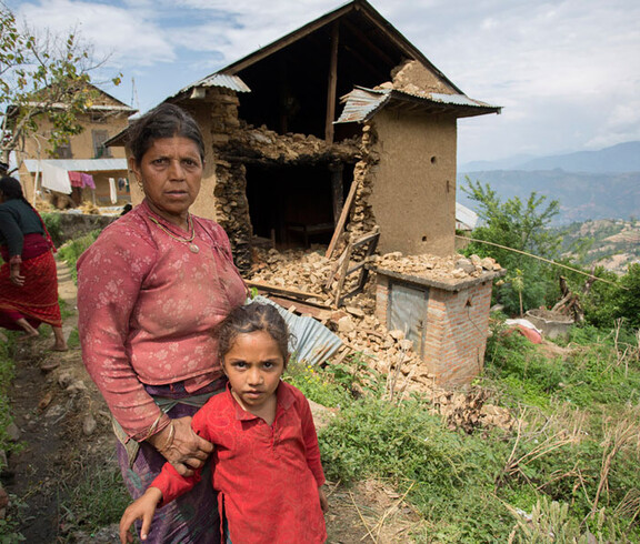 Eine Frau steht mit ihrer Tochter vor den Trümmern ihres Hauses
