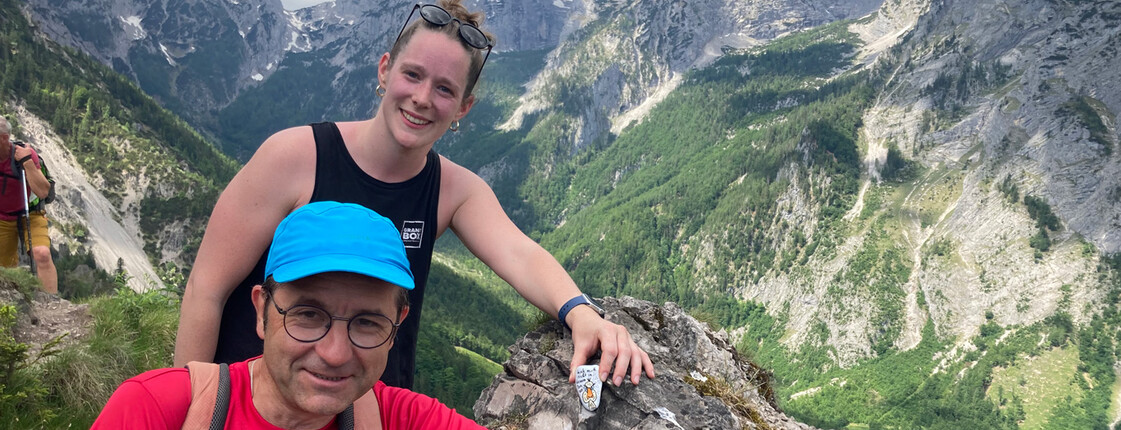 Mann und Frau legen einen bemalten Stein auf einem Berggipfel ab. 