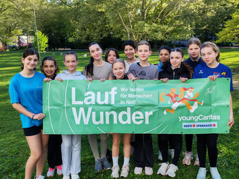 Mehrere Kinder stehen im Freien und halten ein Transparent mit der Aufschrift Laufwunder