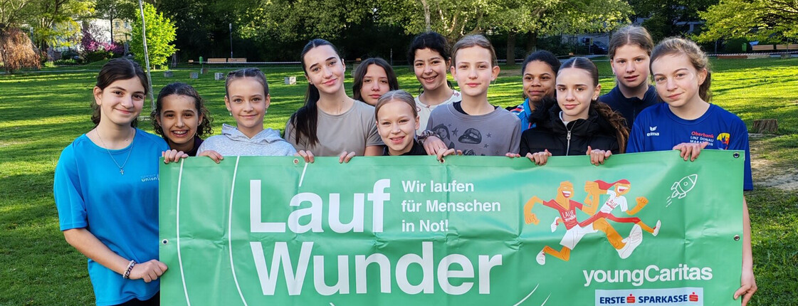 Mehrere Kinder stehen im Freien und halten ein Transparent mit der Aufschrift Laufwunder