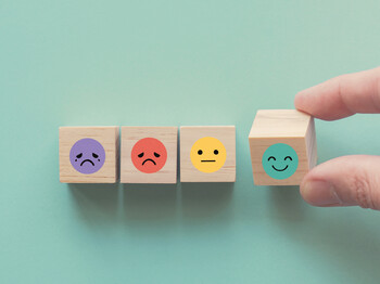 Hand choosing happy smile face wooden block, good feedback rating and positive customer review, mental health assessment, child wellness,world mental health day, think positive, compliment day concept