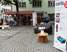 carla stellt wieder Instandgesetzte Möbel in der feldkircher Innenstadt aus. Zwei Roll-ups und eine schwarze Couch stehen am Sparkassenplatz. 