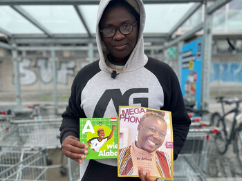 Eine Megaphon Verkäuferin mit dem neuen Megaphon Kinderbuch zur Fußball-WM
