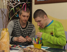 Ein Betreuer arbeitet mit einem Kind, das eine Beeinträchtigung hat, und hilft ihm bei einer kreativen Aktivität im Kinderdorf Gomel.