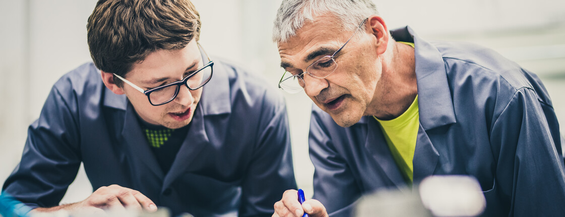 Senior engineer explaining machine functioning to his student