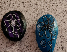 Zwei bemalte Steine mit einem Blumenmotiv