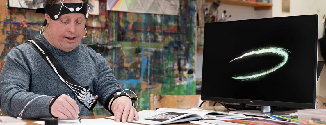 Mann in einem Künstleratelier beim Zeichnen umgeben von einer technischen Ausrüstung.