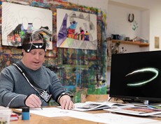 Mann in einem Künstleratelier beim Zeichnen umgeben von einer technischen Ausrüstung.