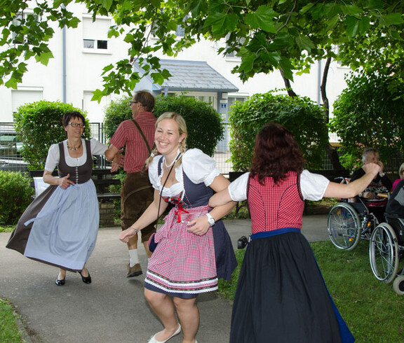 Sommerfest Haus St. Elisabeth tanzende Personen in Dirndl und Lerderhose