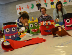 Verzierte, farbige Spendengläser. Man hat den Gläsern Gesichter aufgeklebt.  Siie sind mit Stoff umhüllt und wurden im Lerncafe Lustenau aufgestellt. 