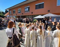 Vor dem Pflegewohnhaus versammelt sich eine große Prozession mit Kindern und Gottesdienstgestaltung, um gemeinsam eine feierliche Andacht im Freien zu feiern.