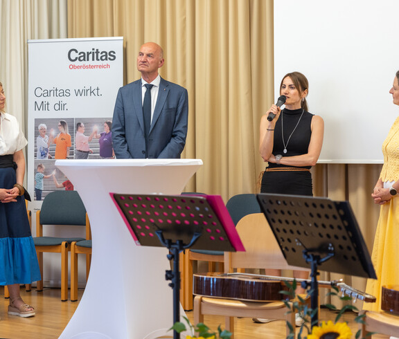 Drei Frauen und ein Mann stehen in einer Runde. Eine Frau spricht ins Mikrofon.