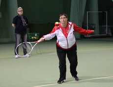 Frau in rotweissrotem Trikot mit Tennisschläger in Action