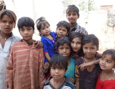 Eine Gruppe von Kindern unterschiedlichen Alters steht eng beisammen und schaut in die Kamera, im Hintergrund eine Mauer.