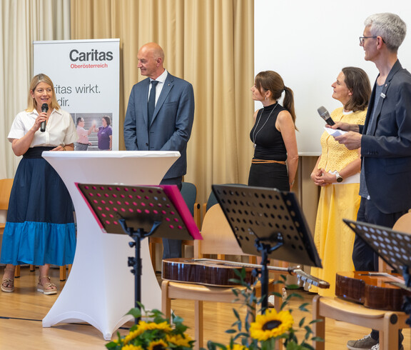 Drei Frauen und zwei Männer stehen auf einer Bühne bei einer Diskussion. 