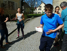 Den Läuferinnen wird ein Strich auf ihre Laufnummer gemacht. Die Sonne scheint.