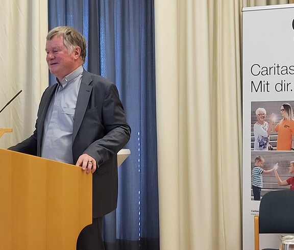Mann hinter dem Rednerpult spricht ins Mikrofon