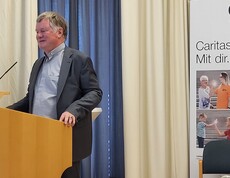 Mann hinter dem Rednerpult spricht ins Mikrofon