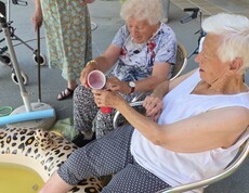 Bewohnerinnen und Bewohner aus unserem Pflegewohnhaus genießen gemeinsam eine erfrischende Abkühlung auf der Terrasse.