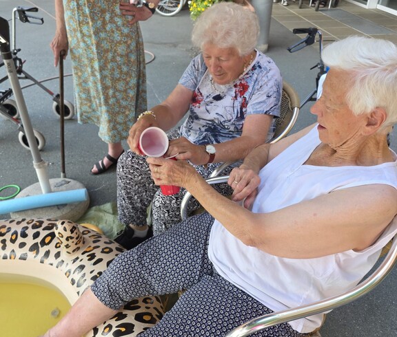 Bewohnerinnen und Bewohner aus unserem Pflegewohnhaus genießen gemeinsam eine erfrischende Abkühlung auf der Terrasse.