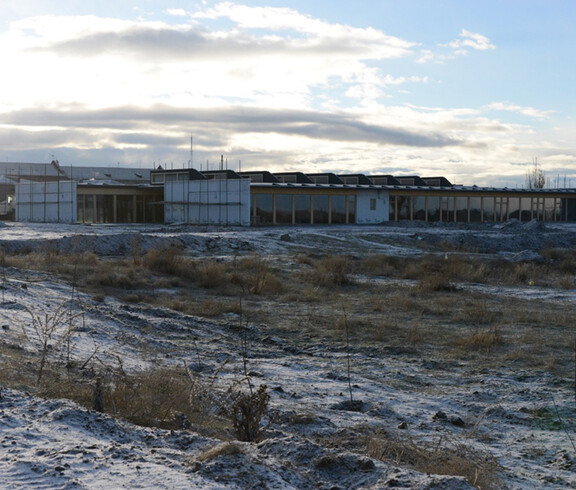 Die Unterkunft von "Emils kleine Sonne" in Armenien von außen. Es ist ein größeres Gebäude, das in Mitten eines Felds steht und es besitzt viele Fenster, damit die Räume gut ausgeleuchtet sind. 