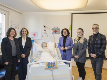 Vier Frauen und ein Mann stehen um ein Pflegebett