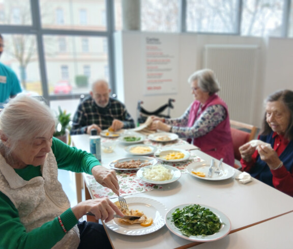 Senior*innen sitzen am gedeckten Tisch und genießen gemeinsam ein tunesisches Gericht.
