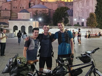 Drei Männer stehen hinter einem Tandemfahrrad vor der Blauen Moschee in Istanbul.