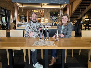 David Gölles & Nora Tödtling-Musenbichler, Direktorin Caritas Steiermark sitzen vor den Essigen von Gölles