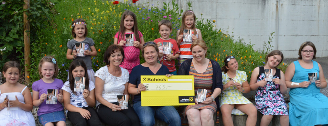 Kinderchor Montafon spendet 765 Euro für die Auslandshilfe. Gruppenfoto des Chors. In der Mitte sitzt Caritas-Mitarbeiterin Mirjam Vallaster. 