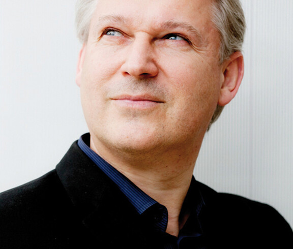 Ein Herr mittleren Alters schaut in die Höhe. Er trägt ein Hemd mit einem Sakko.