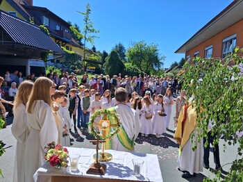 Vor dem Pflegewohnhaus versammelt sich eine große Prozession mit Kindern und Gottesdienstgestaltung, um gemeinsam eine feierliche Andacht im Freien zu feiern.