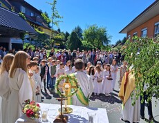 Vor dem Pflegewohnhaus versammelt sich eine große Prozession mit Kindern und Gottesdienstgestaltung, um gemeinsam eine feierliche Andacht im Freien zu feiern.