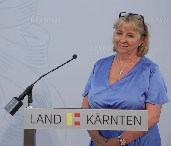 Direktorin Mag.a Tanja Perchtold steht vor einem Pult mit Mikrofon