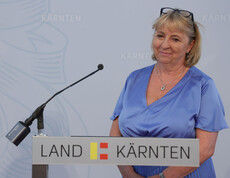 Direktorin Mag.a Tanja Perchtold steht vor einem Pult mit Mikrofon