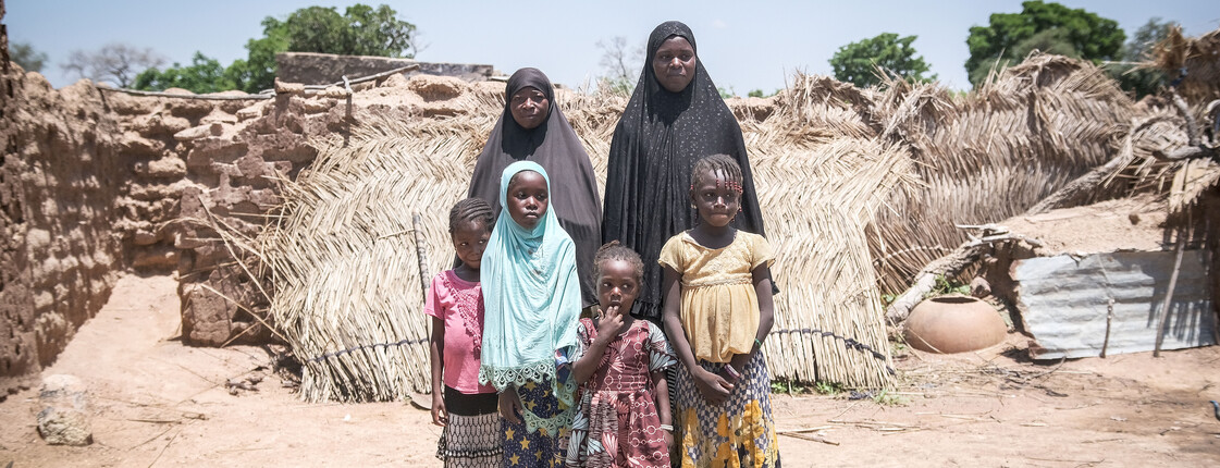 Gruppenfoto von zwei Frauen mit ihren Töchtern vor den Trümmern einer Siedlung in Burkina Faso.