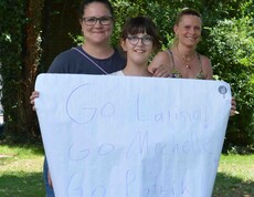Drei Mädchen feuern eines beim Go Kart Rennen mit einem Plakat an 