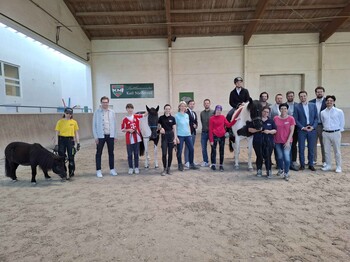 Viele Menschen und ein Pferd in einer Reithalle
