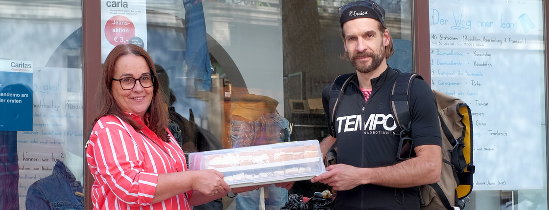 Ein Fahrradbote übergibt ein Tablett mit Kuchen.