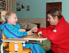 Eine Betreuerin spielt mit einem Kind im Kinderdorf Gomel und unterstützt es bei einer interaktiven Aktivität.