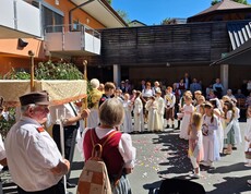 Vor dem Pflegewohnhaus versammelt sich eine festliche Prozession mit Erstkommunionskindern und Gläubigen zu einer feierlichen Segnung im Freien.