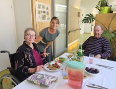 Beim Sommerfest im Pflegewohnhaus steht die Hausleiterin zwischen zwei Bewohnern an einem festlich gedeckten Tisch und verbringt gemeinsam mit den Gästen einen geselligen Nachmittag in freundlicher Atmosphäre.