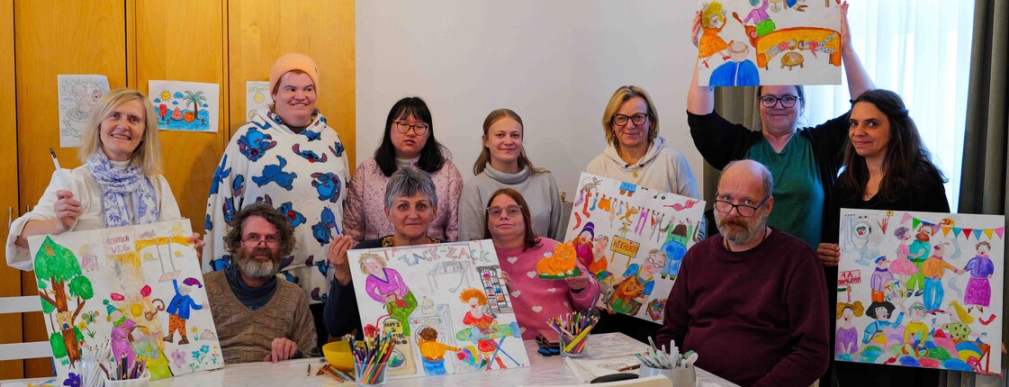 Viele Personen malten an einem Kunstwerk und zeigen Ergebnisse