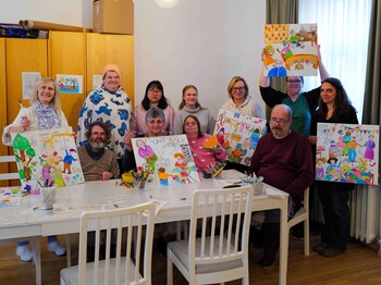 Viele Personen malten an einem Kunstwerk und zeigen Ergebnisse