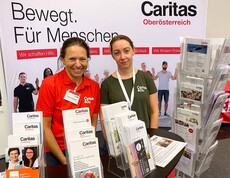 Zwei Frauen am Caritas Messestand mit vielfältigem Informationsangebot